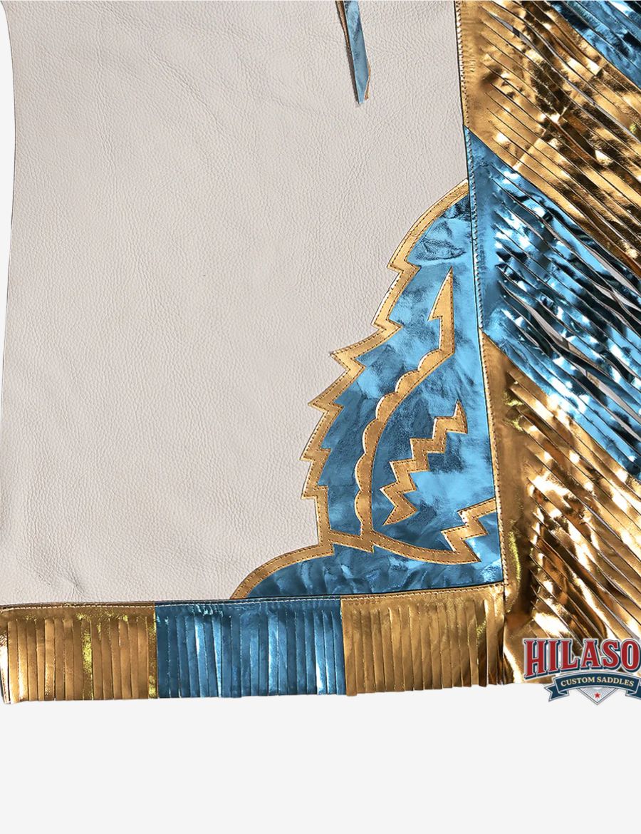 Detailed fringe view of white rodeo chaps with metallic blue and gold leather fringe and western corner overlays.
