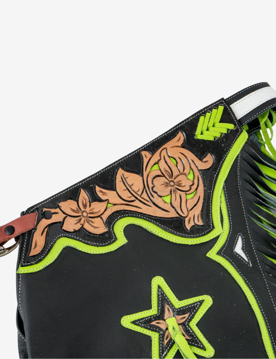 Close-up yoke view of black rodeo chaps featuring floral tooling and neon green western overlay details.