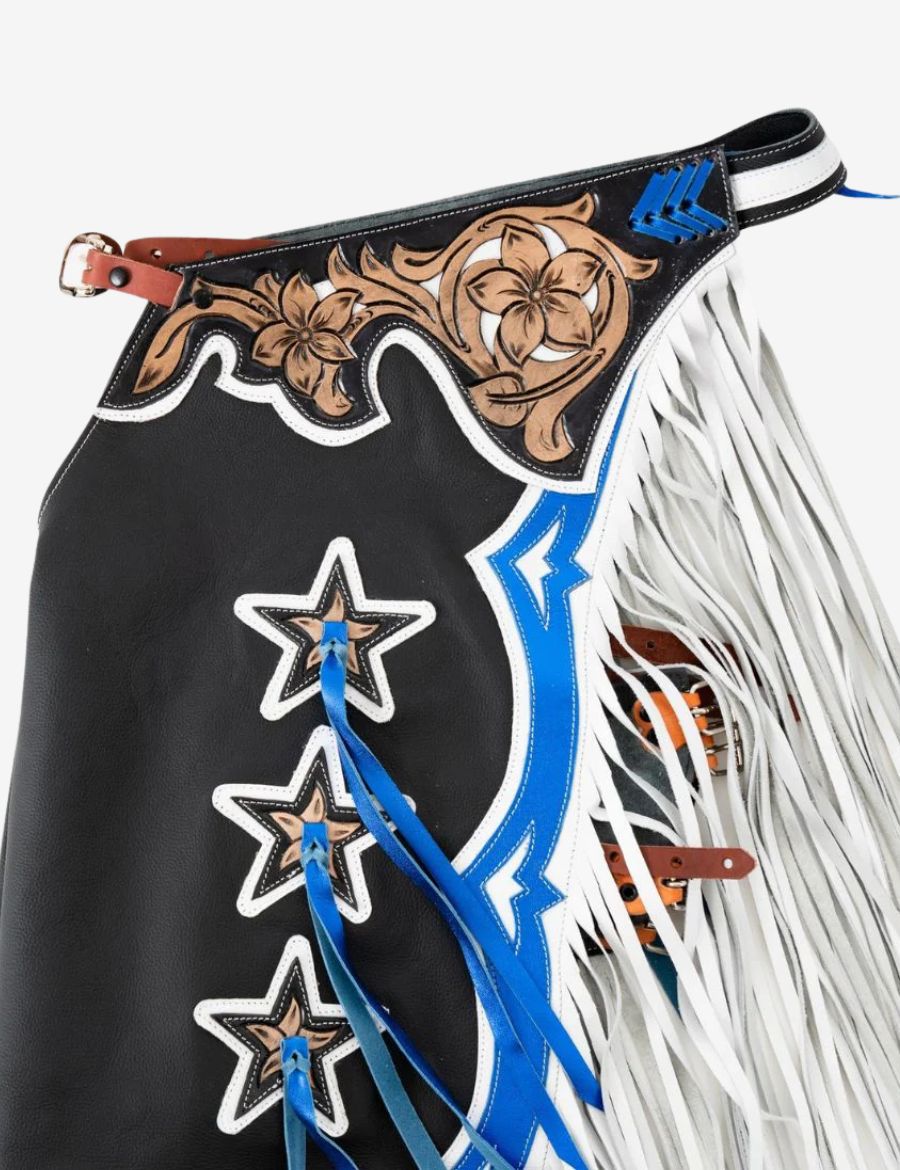 Close-up yoke view of black rodeo chaps featuring hand tooled floral leather and blue western accents.