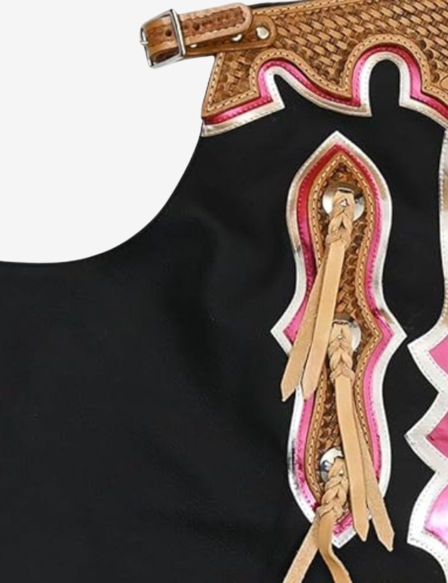 Close-up tooling detail on black rodeo chaps featuring basket tooled leather, metallic pink trim, and braided accents.
