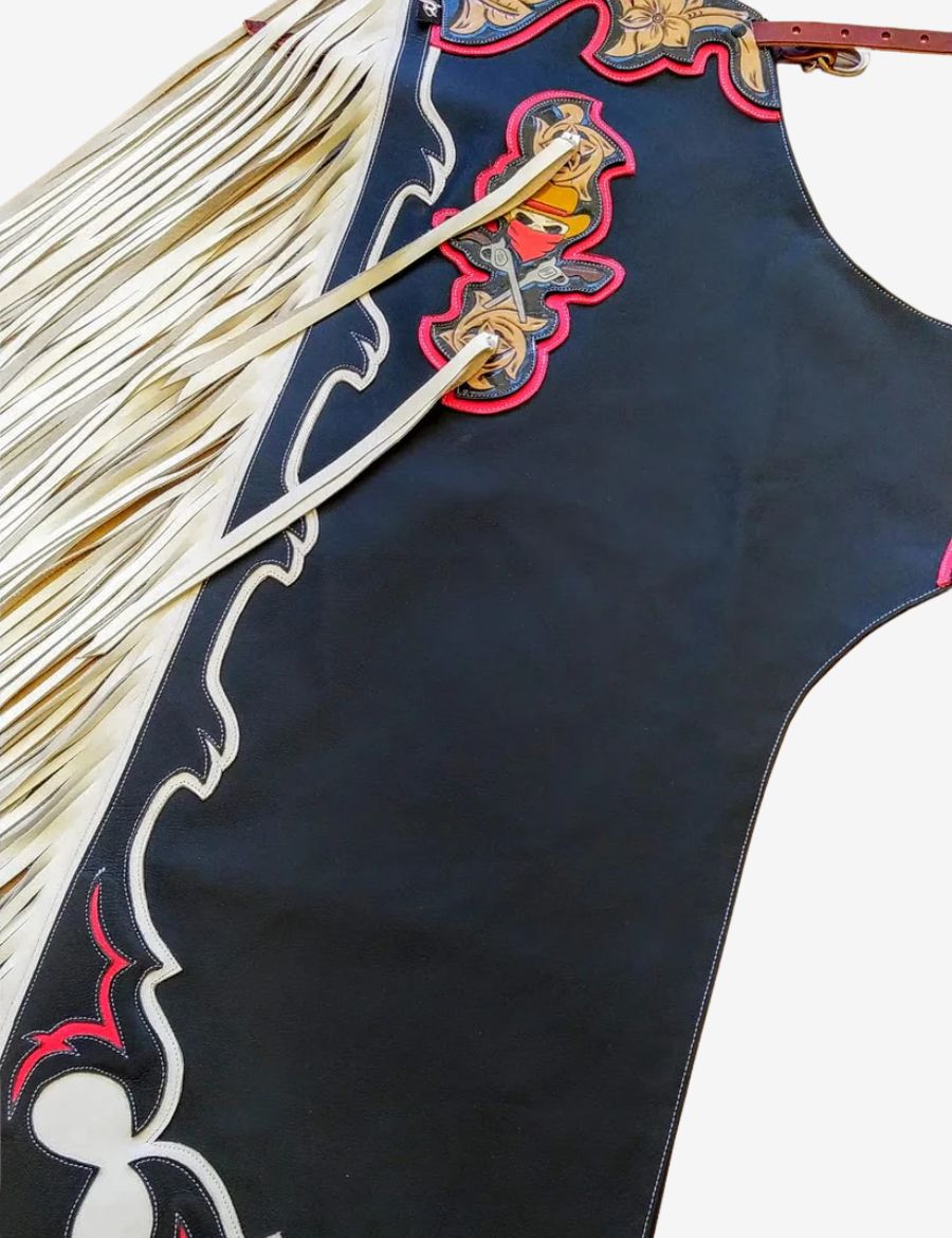 Side detail view of black rodeo chaps with flowing white fringe, western trim, and decorative rodeo leather artwork.