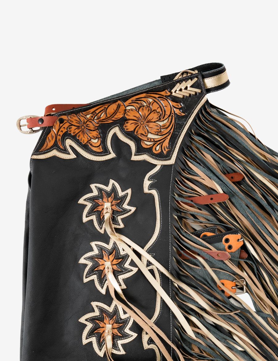 Detailed yoke view of black leather rodeo chaps with hand tooled floral leather and western buckle accents.