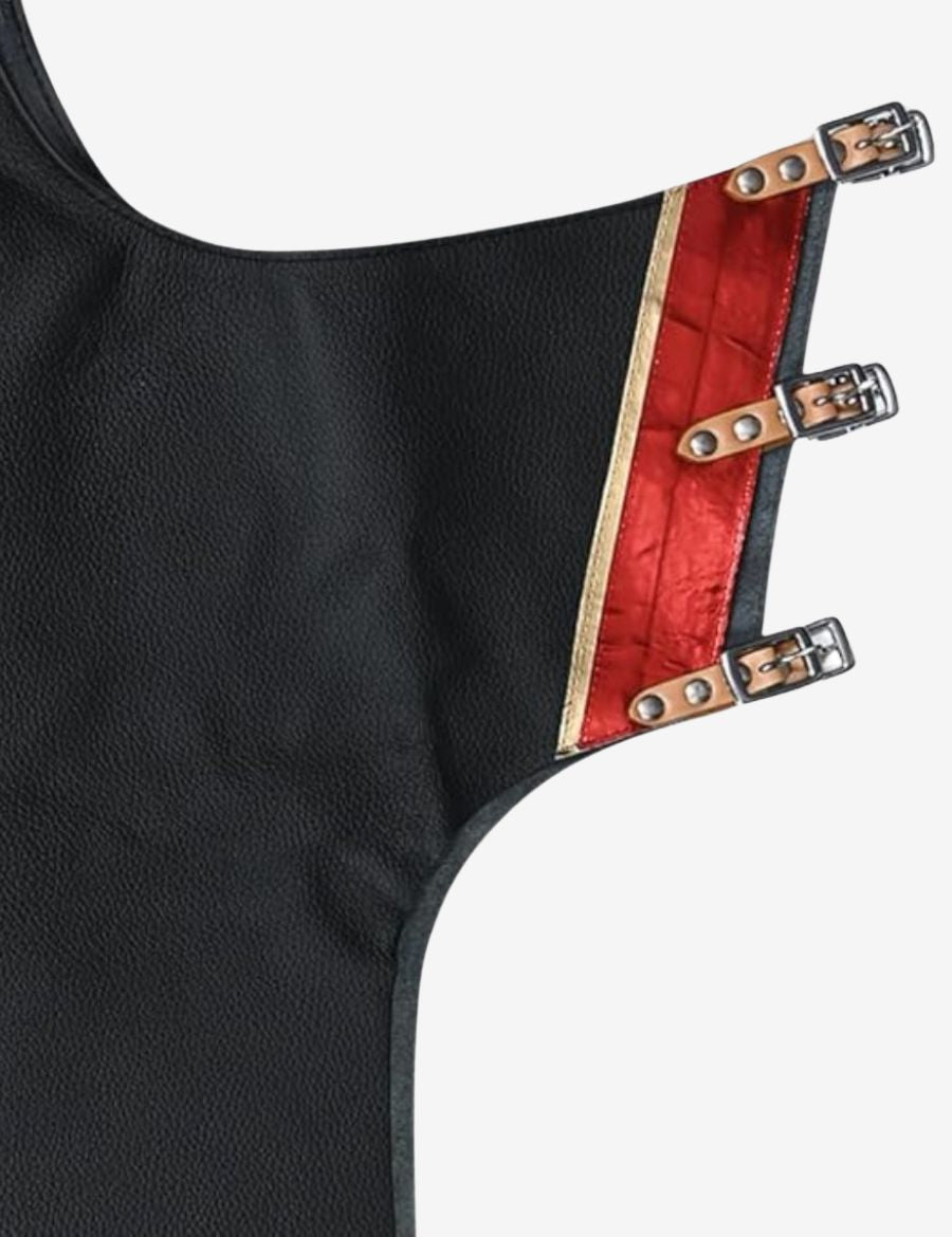 Close-up tooling detail of black leather rodeo chaps featuring hand tooled western patterns and metallic red accents.