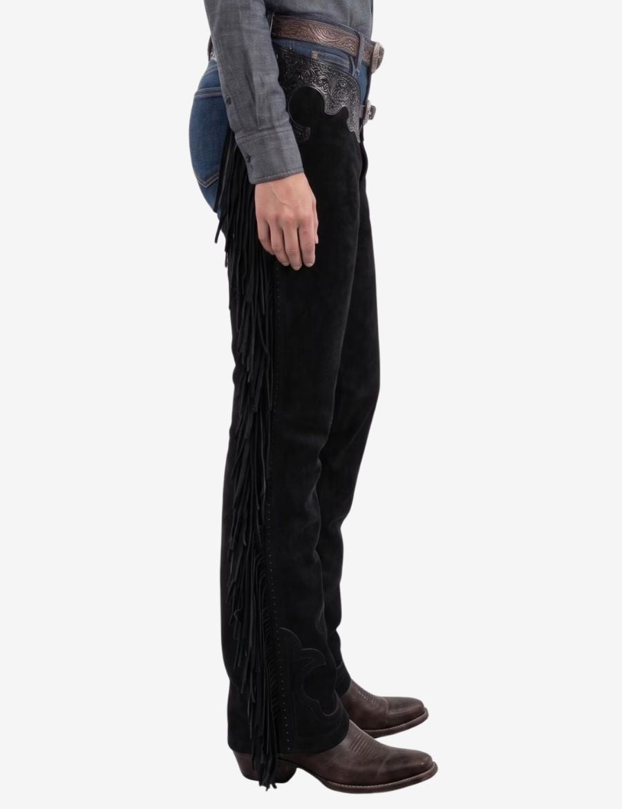 Side profile of black tooled womens western chaps highlighting flowing fringe, embossed leather yoke, and traditional western styling.