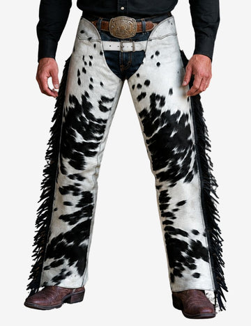 Model wearing black and white hair-on hide western chaps with authentic cowhide texture and cowboy outfit styling.