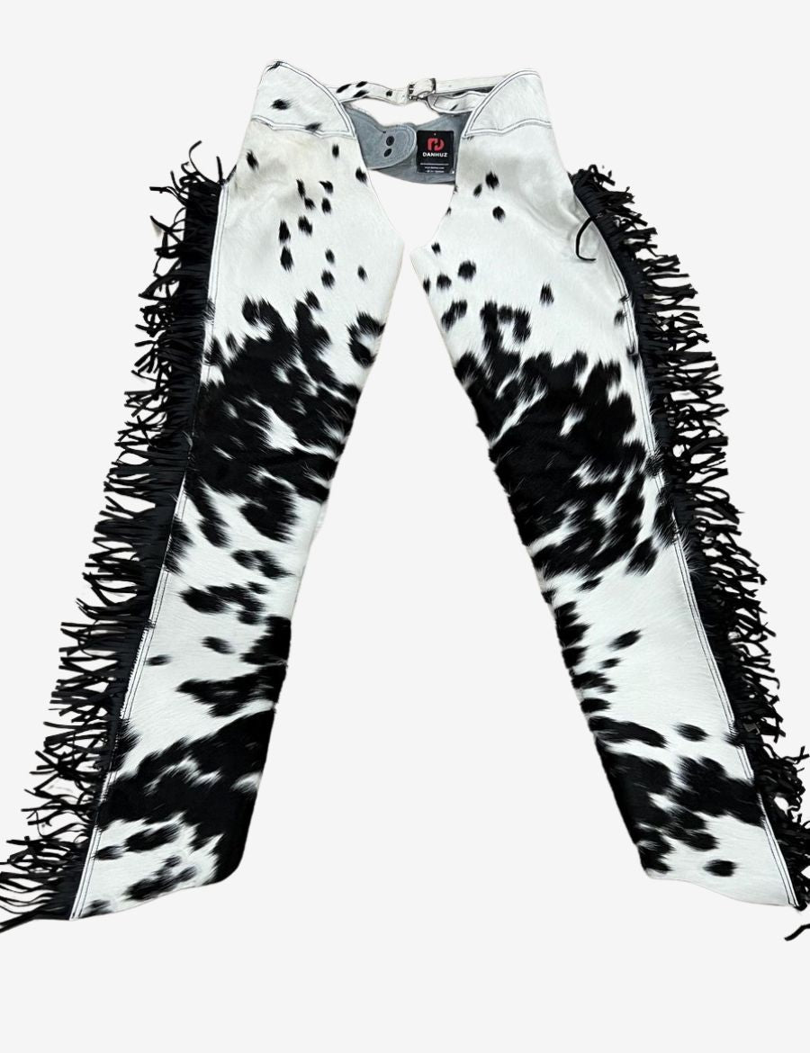 Model wearing black and white hair-on hide western chaps with authentic cowhide texture and cowboy outfit styling.