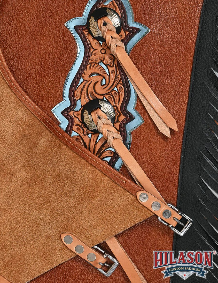 Inside suede view of brown and black bull riding chaps featuring adjustable buckle straps and hand-tooled leather paneling.