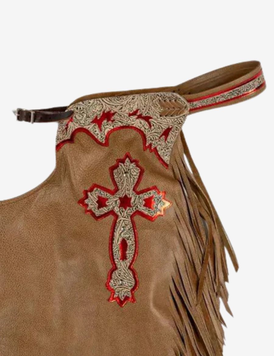 Close-up cross detail view of brown bull riding chaps with engraved tooling and red metallic leather accents.