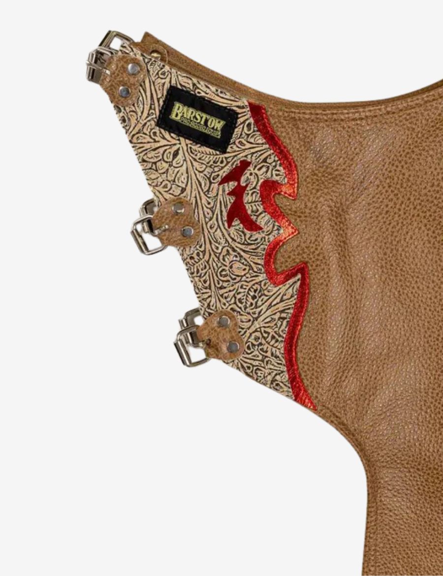 Inside buckle view of brown leather rodeo chaps featuring engraved western tooling and adjustable leg straps.