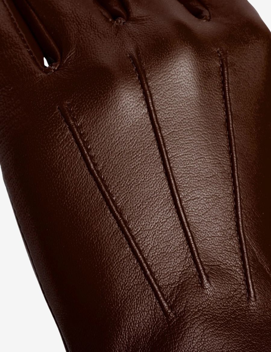 Close up of brown leather riding gauntlet gloves highlighting premium leather texture, stitching details, and craftsmanship.