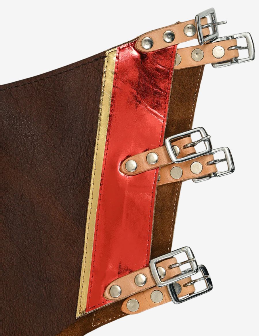 Lower leg close-up of brown leather rodeo chaps with metallic orange fringe and detailed western tooling.