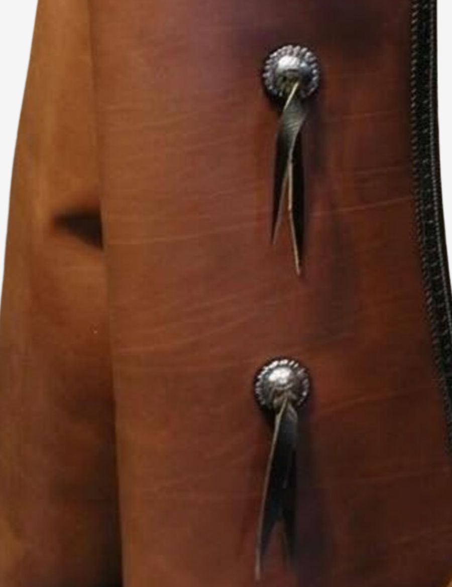 Close-up detail of brown leather batwing chaps showcasing concho accents and premium western craftsmanship.