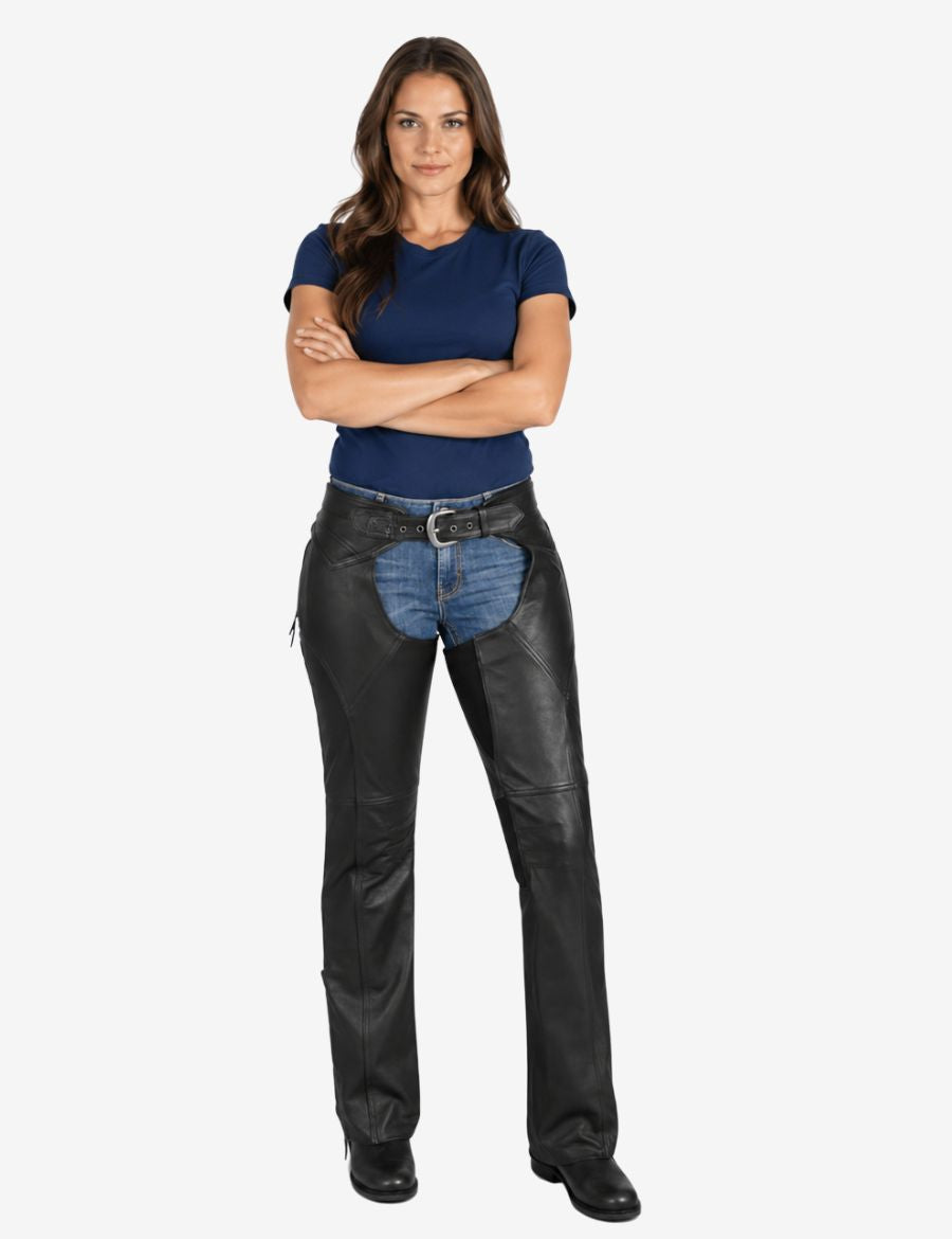 Female model wearing contour fit black motorcycle chaps with fitted riding stance and protective leather construction over jeans.