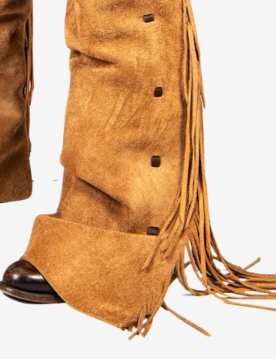 Detailed close-up of fringe and snap button accents on tan suede cowboy show chaps.