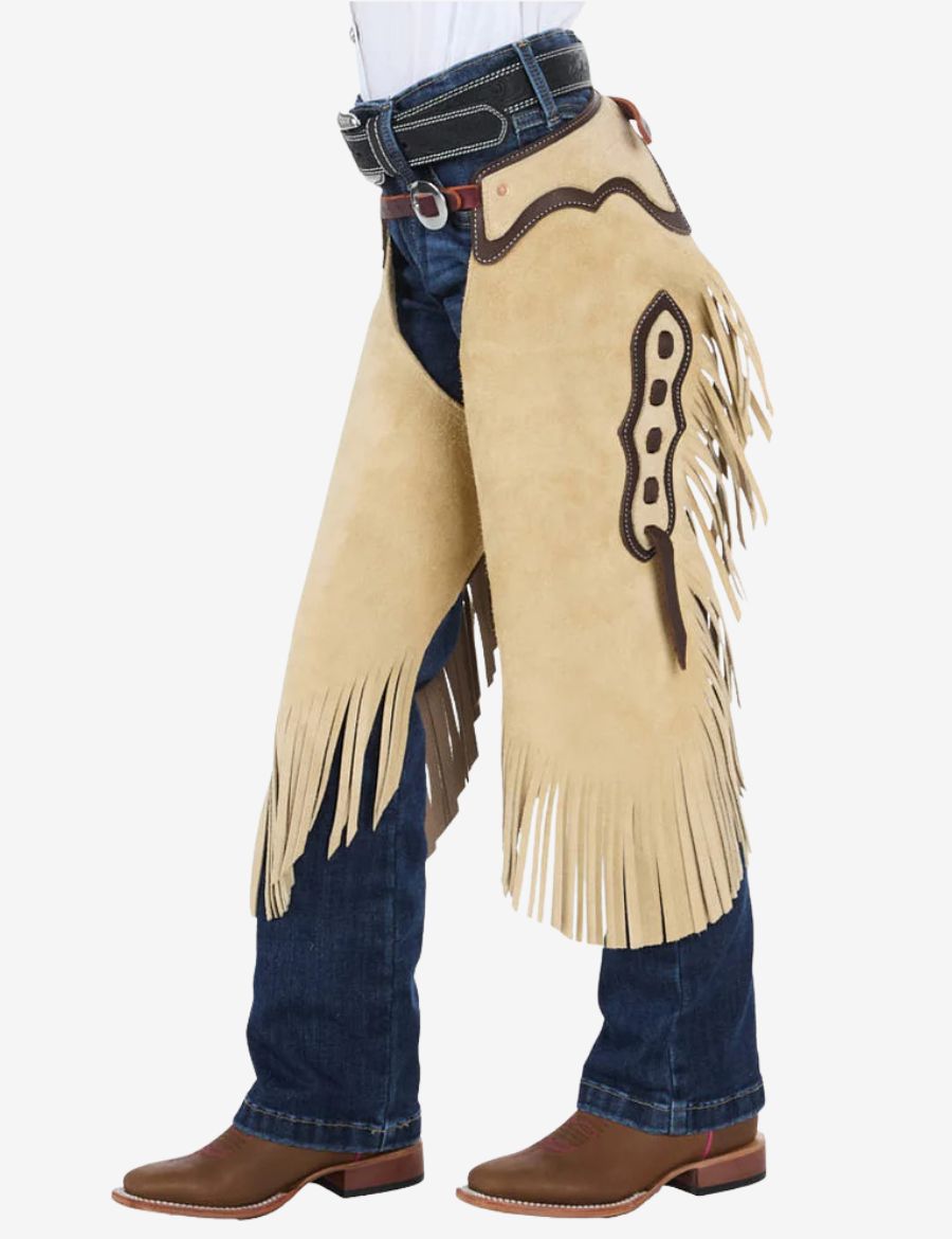 Angled side view of cowboy cream suede chinks chaps with flowing fringe, dark leather accents, and western styling.