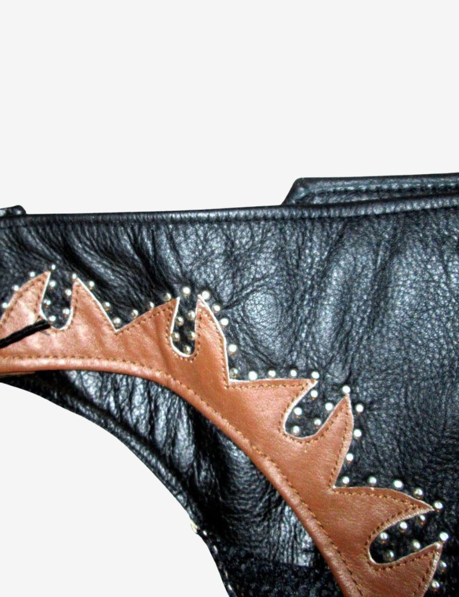 Close-up of brown studded leather trim on black cowhide men’s western chaps.