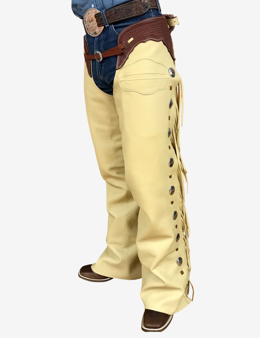Angled side view of cream western leather shotgun chaps with silver conchos, fringe accents, and cowboy styling.