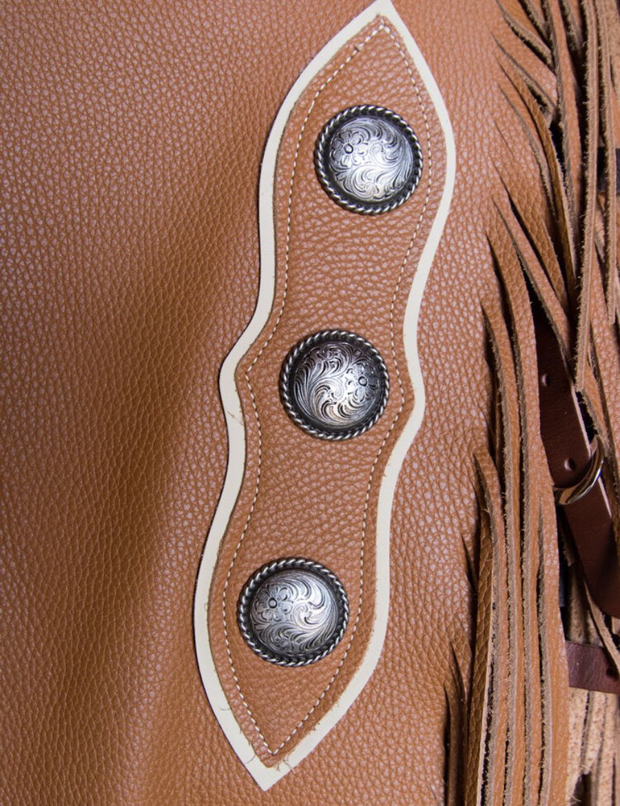 Close-up detail of western concho leather chinks chaps showing engraved silver conchos, stitching, and fringe accents.