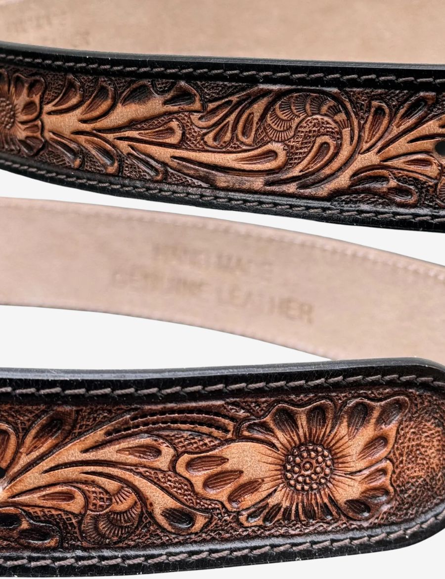 Folded brown western leather belt showcasing floral tooling and traditional cowboy craftsmanship.