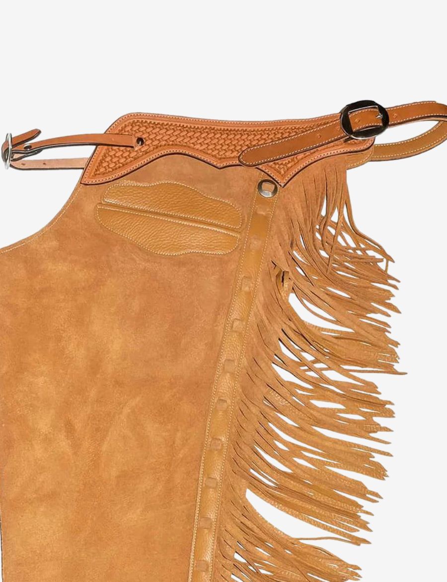 Close-up side detail of tan suede cowboy chaps featuring braided yoke, leather fringe, and reinforced trim.
