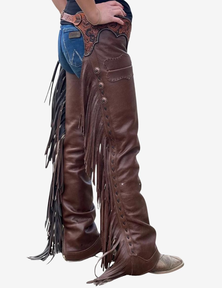 Side view of leather women western shotgun chaps with long fringe accents, decorative tooling, and durable riding-ready construction.