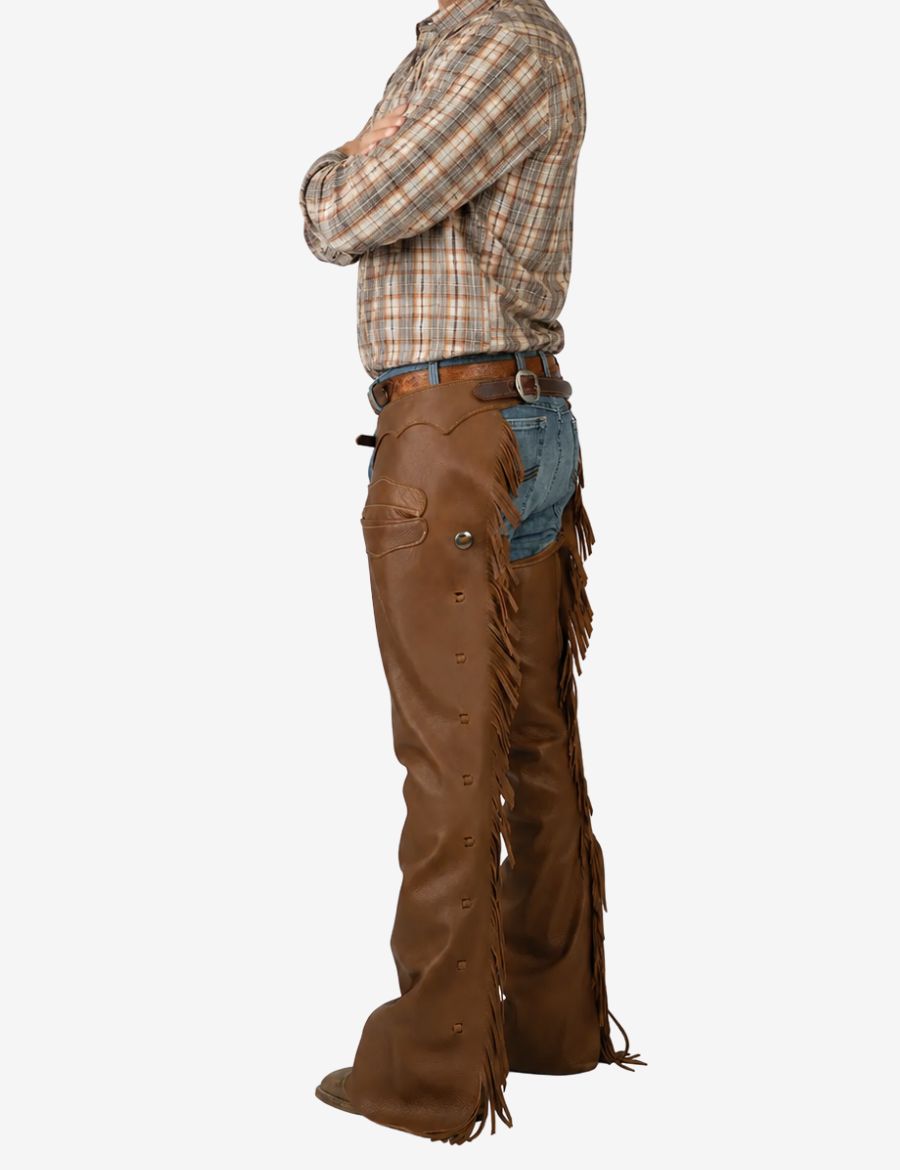 Mens saddle brown leather western chaps worn by model featuring western fringe detailing and adjustable belt fit.