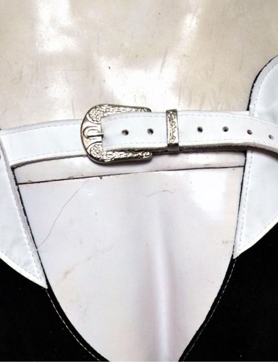 Detailed view of decorative silver buckle belt on mens western black and white fringe chaps.
