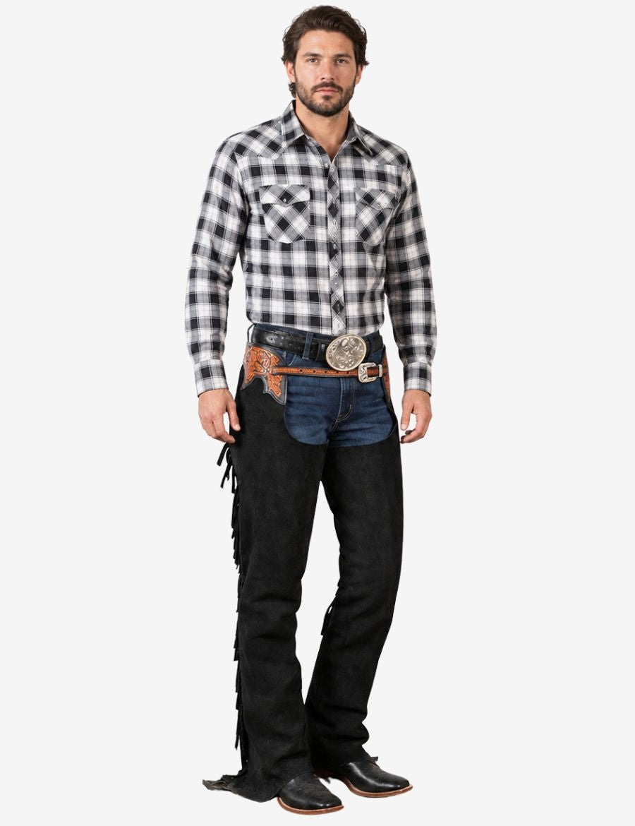 Male model wearing premium black suede western cowboy chaps with engraved leather yokes and long fringe detailing.