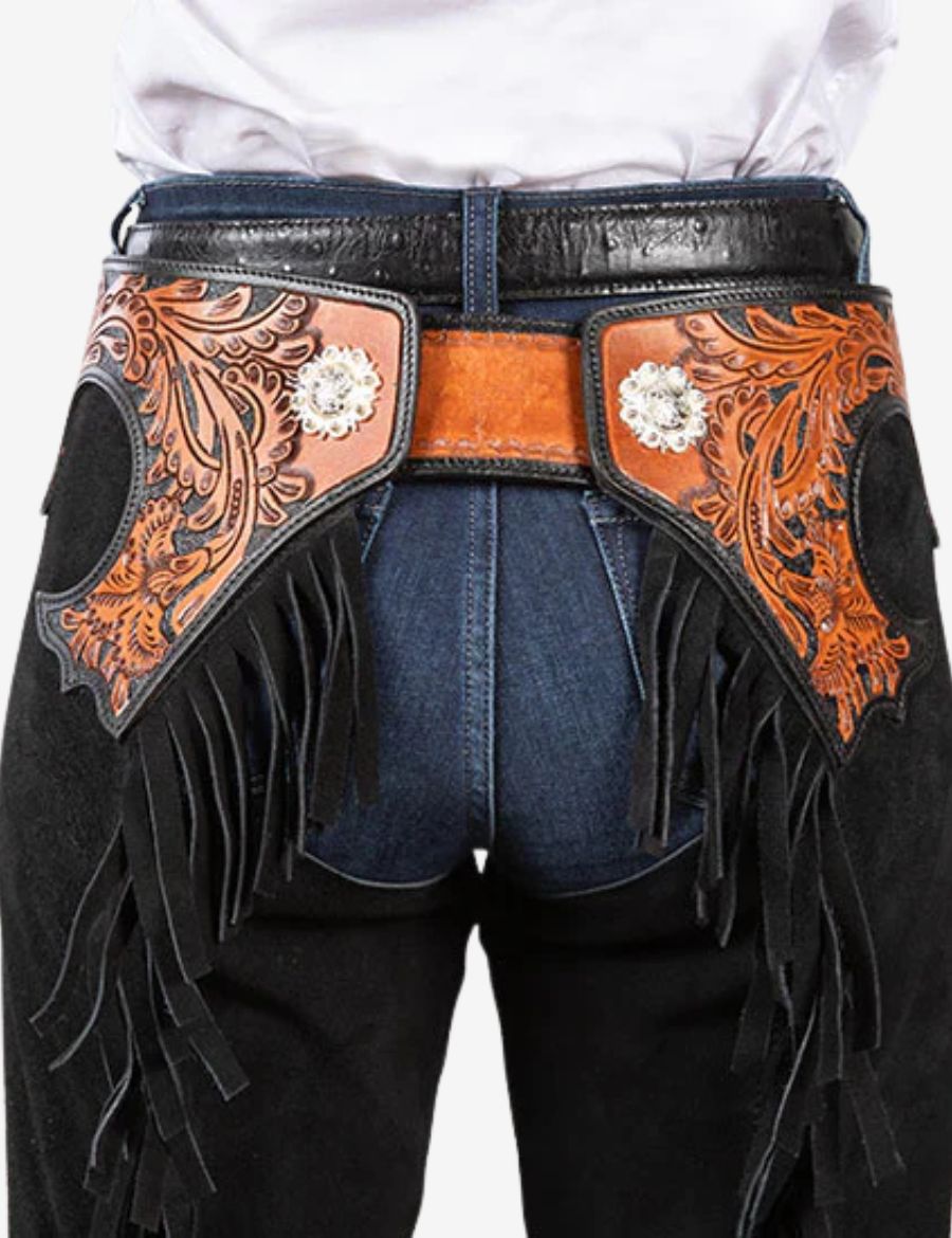 Back waist detail of premium black suede cowboy chaps with floral tooled leather panels and western fringe accents.
