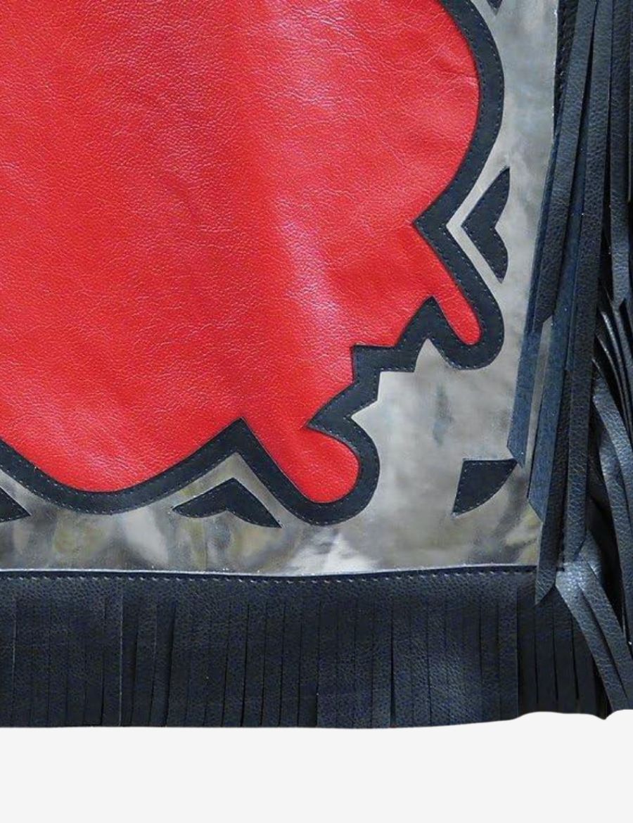 Close-up fringe view of red leather bull riding chaps with black fringe and silver western overlay trim.