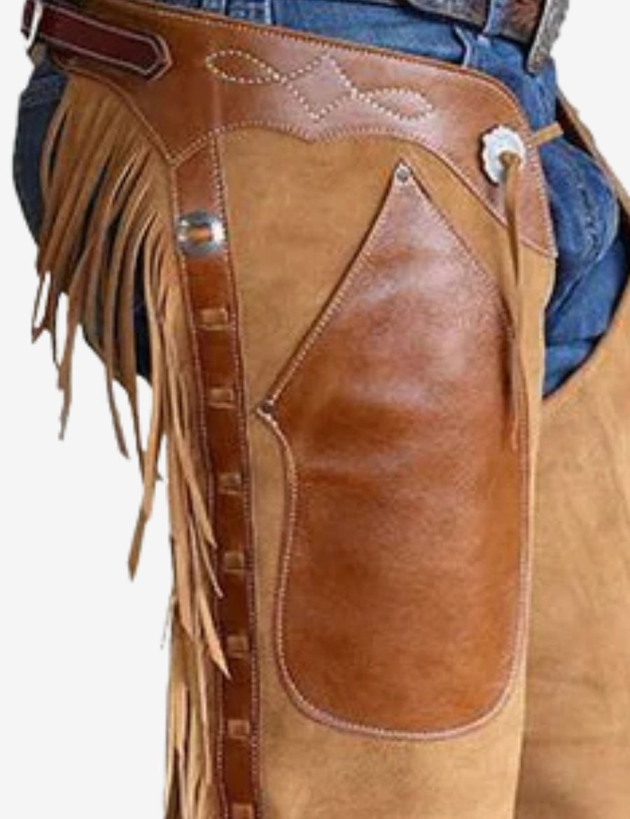 Close-up detail of tan suede shotgun chaps highlighting leather overlay panels, fringe accents, and western stitching.