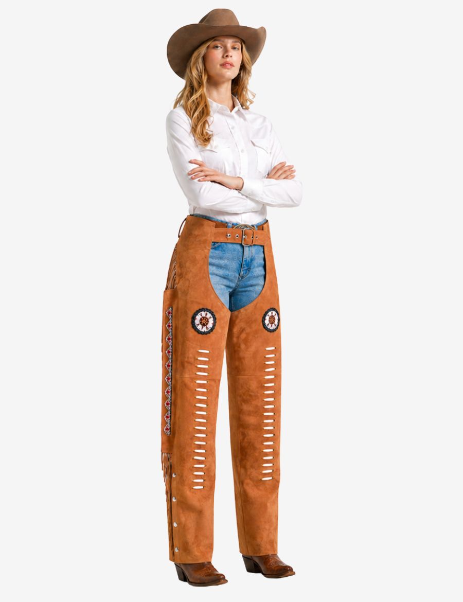 Female model wearing tan suede western chaps for women featuring cowgirl styling, fringe accents, and rodeo appeal.