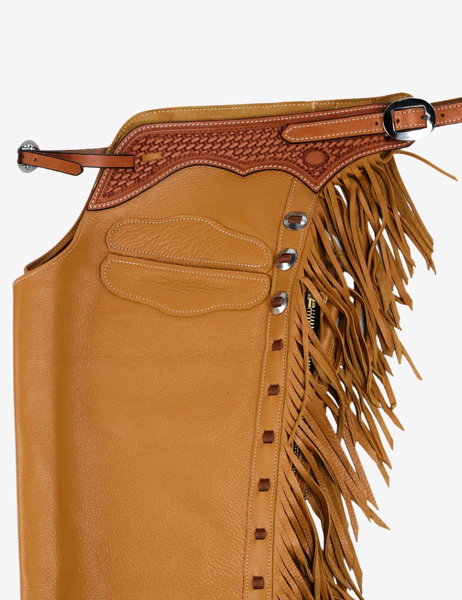 Side view of tooled leather cowboy shotgun chaps with long fringe, braided yoke, and tan western riding design.