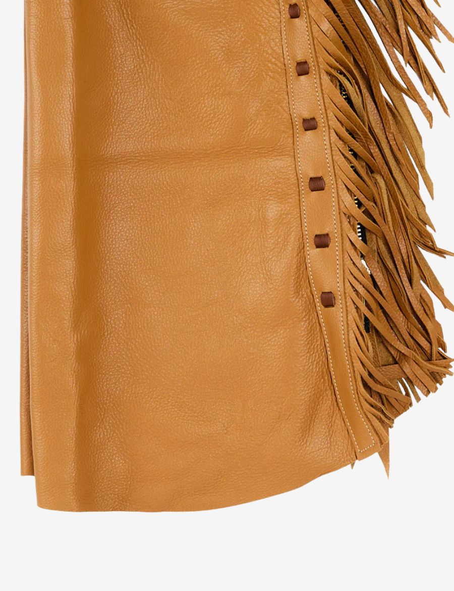 Close-up detail of tan leather cowboy shotgun chaps highlighting grain texture, laced edge, and long fringe.
