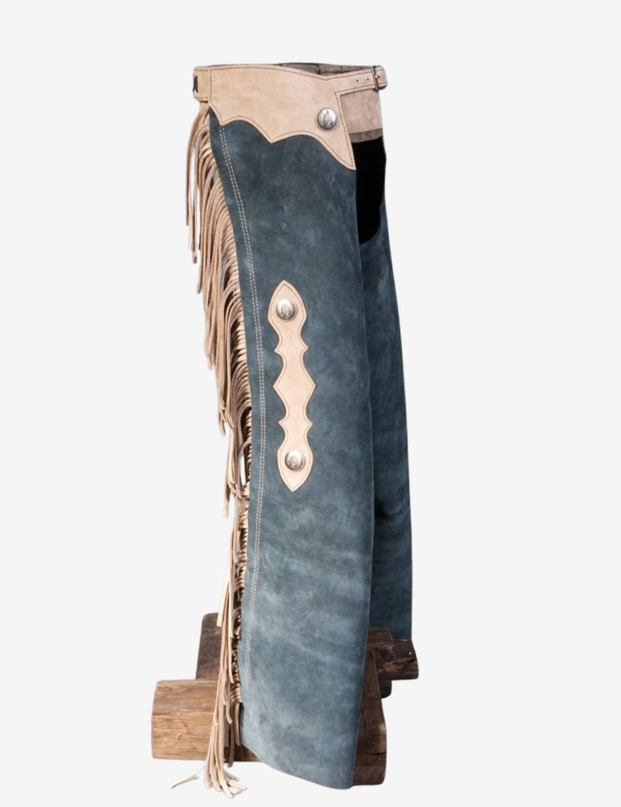 Angled front view of vintage blue suede cowboy chaps featuring long beige fringe and western accents.
