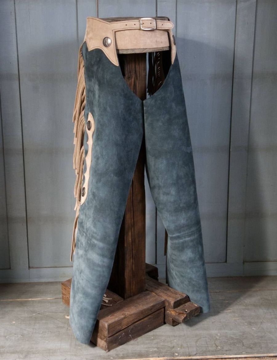 Front product view of vintage blue suede fringe cowboy chaps with beige trim and western styling.