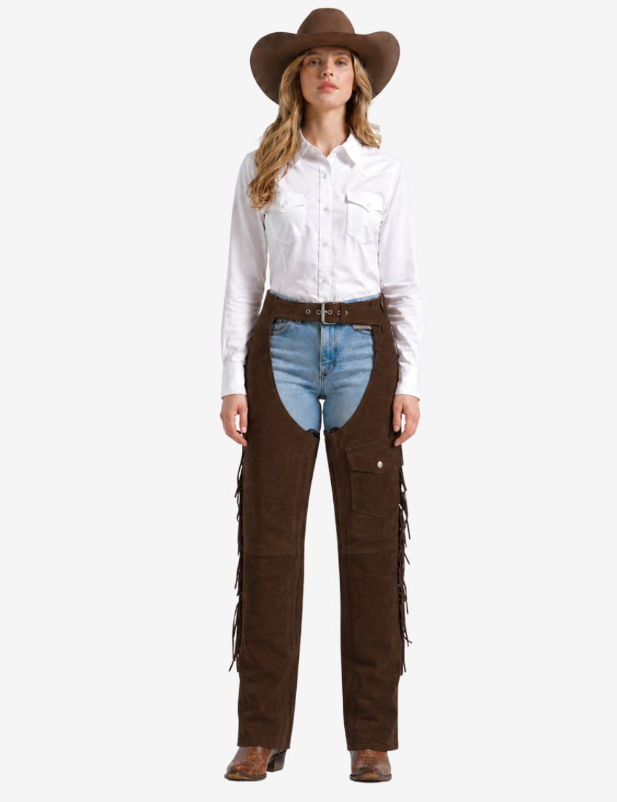 Female model wearing walnut womens western chaps with fringe paired with cowboy boots and western shirt.