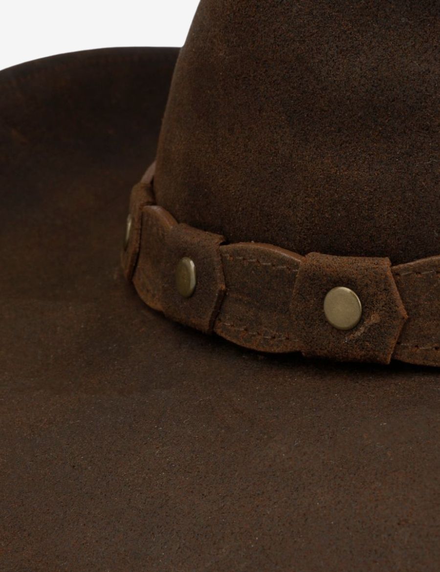 Close-up of western brown suede leather cowboy hat featuring a distressed leather hatband with antique rivet detailing.