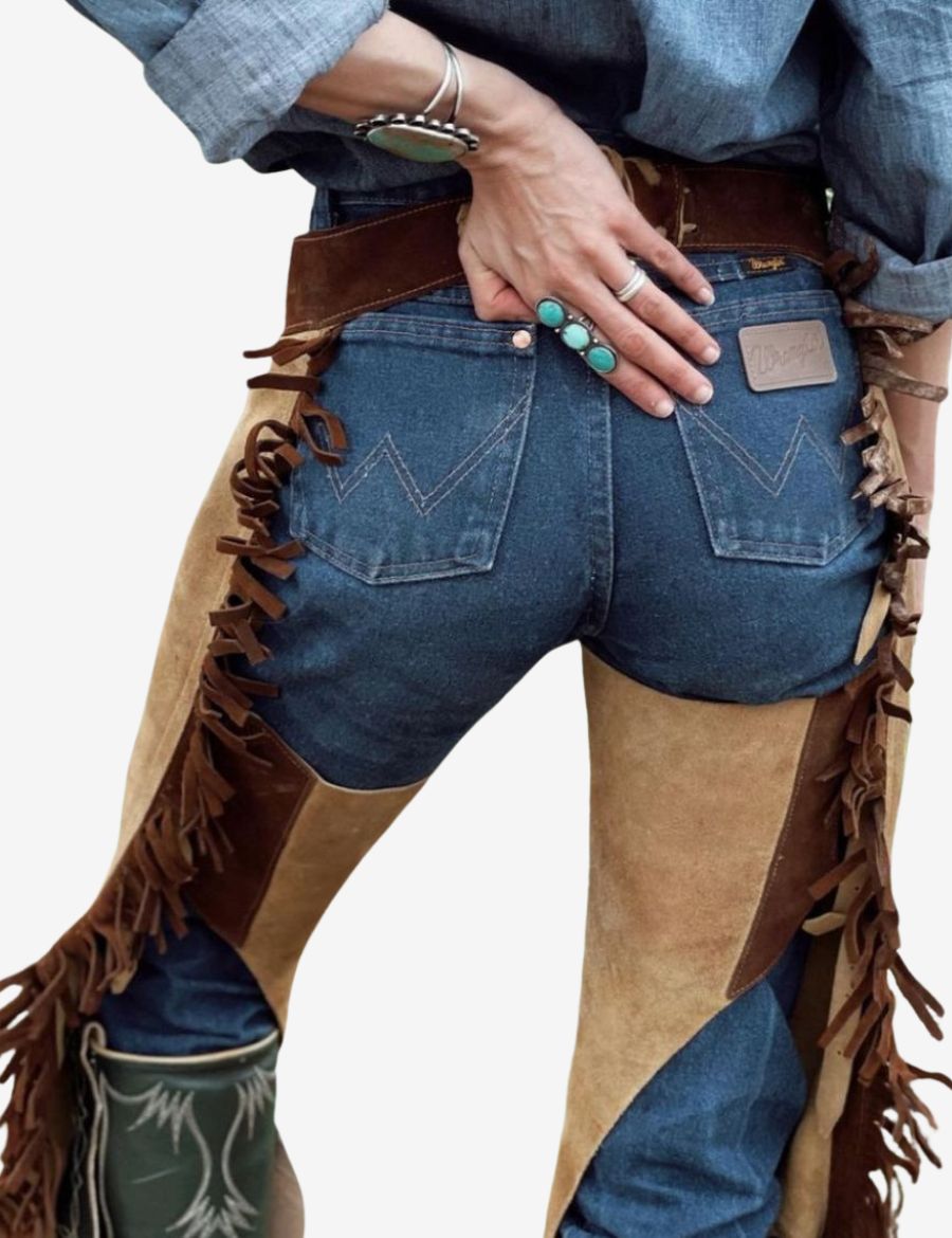 Back detail view of western buckskin cowgirl chaps with leather side lacing and fringe trim accents.