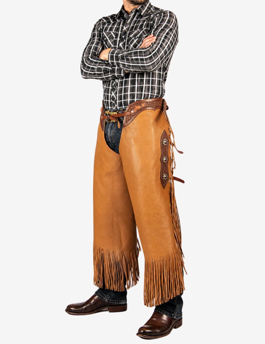 Cowboy wearing western cognac cowhide chinks chaps with durable leather construction and traditional western riding design.