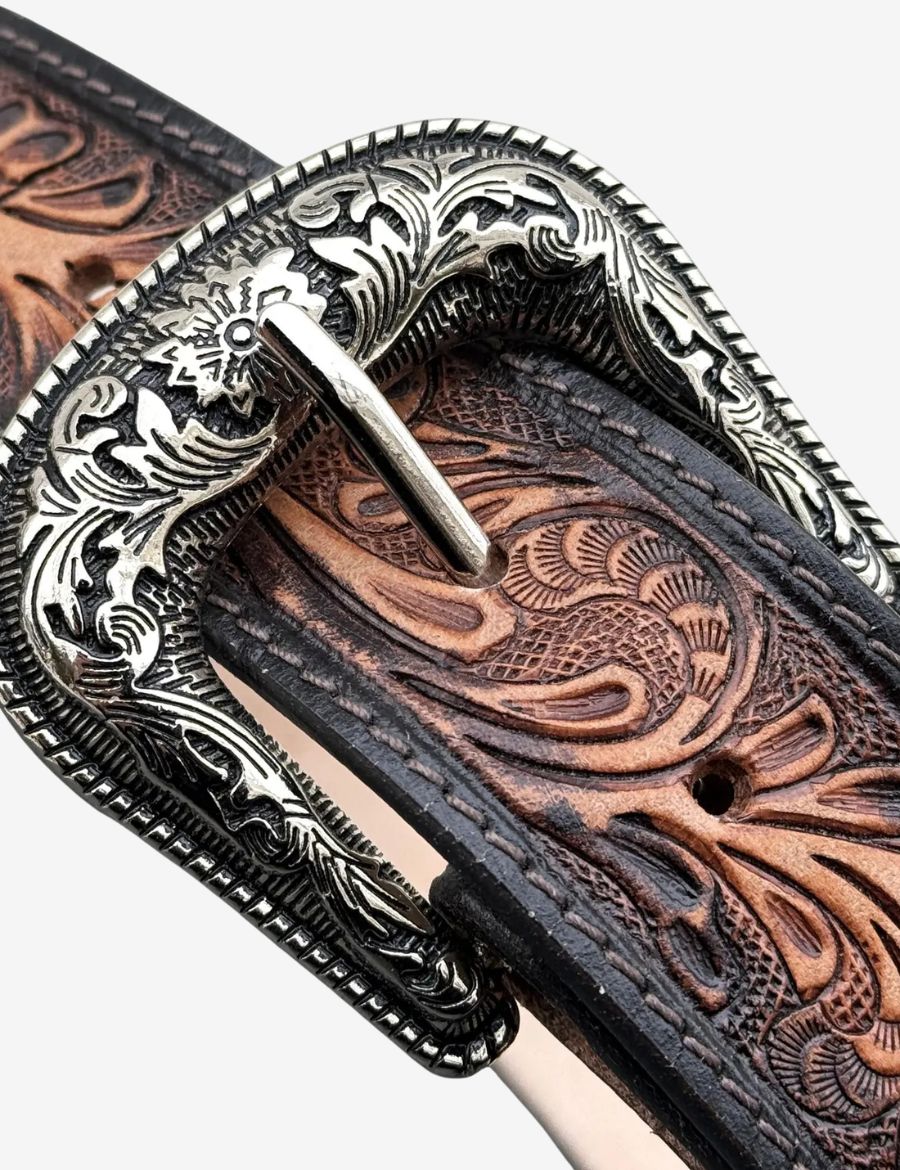 Brown leather western belt featuring hand tooled floral carvings and an engraved silver cowboy buckle.