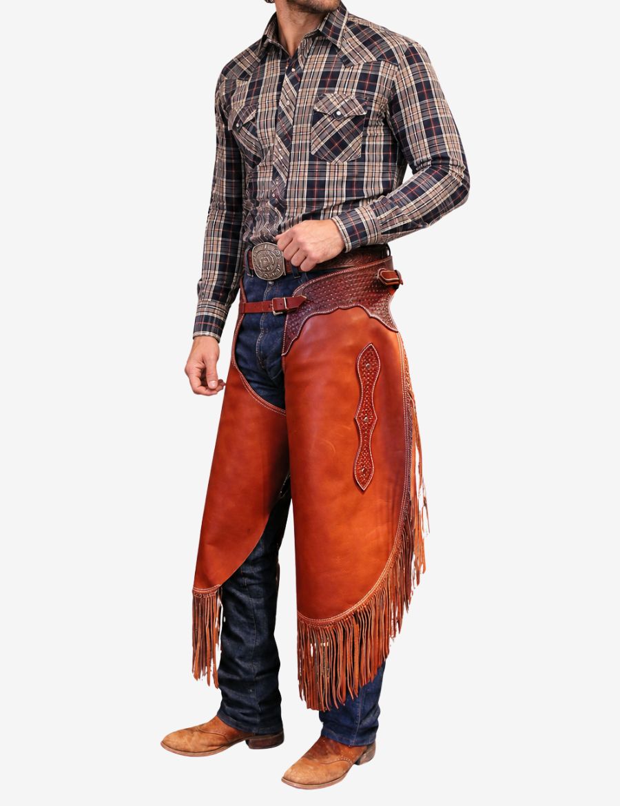 Western heritage trim chinks chaps styled on cowboy model with rich leather finish, western tooling, and classic fringe detailing.