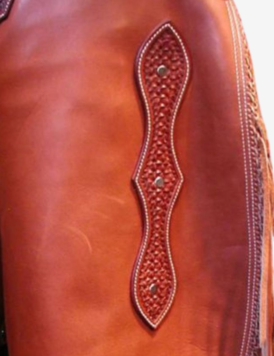 Close-up of hand-tooled leather detail on western heritage trim chinks chaps with decorative craftsmanship and rugged cowboy styling.