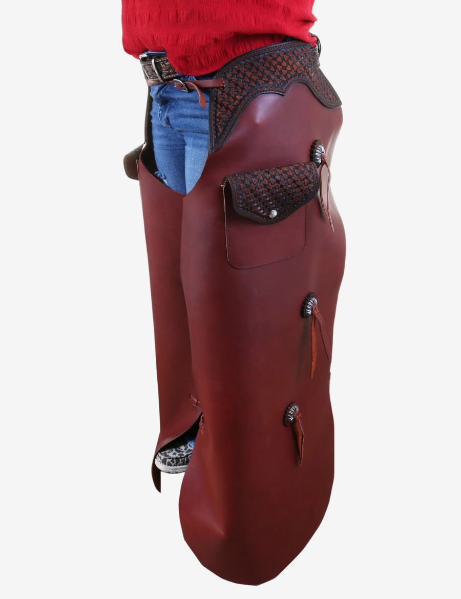 Front view of western tooled leather batwing chaps with basketweave yoke, pocket, and concho accents.