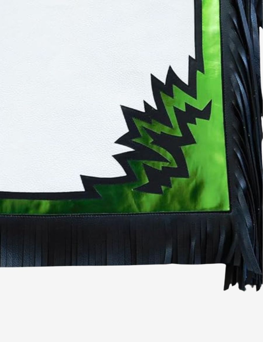 Lower leg detail of white rodeo chaps with metallic green overlay, black fringe, and bold western pattern accents.